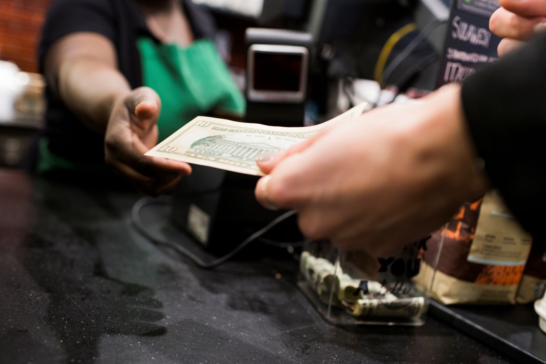 a-customer-hands-over-cash-for-a-cannabis-purchase-at-a-dispensary customer handing over cash for a cannabis purchase at a dispensary