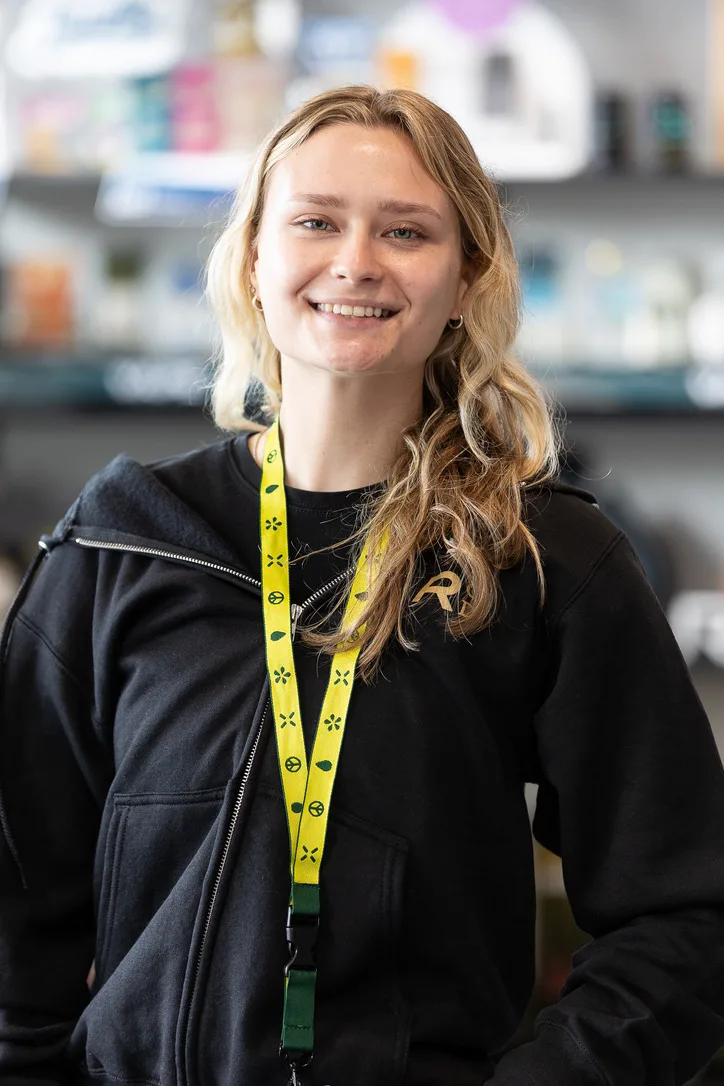 Team member in yellow lanyard smiling in front of product displays
