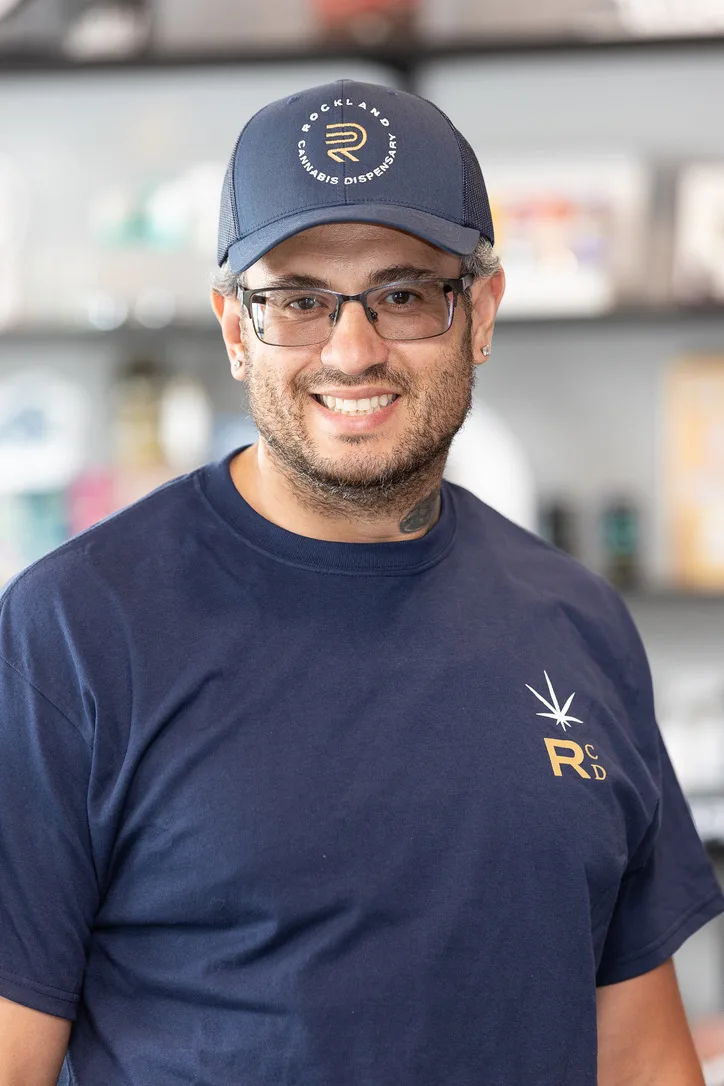Team member in a branded cap and navy tee smiling at work